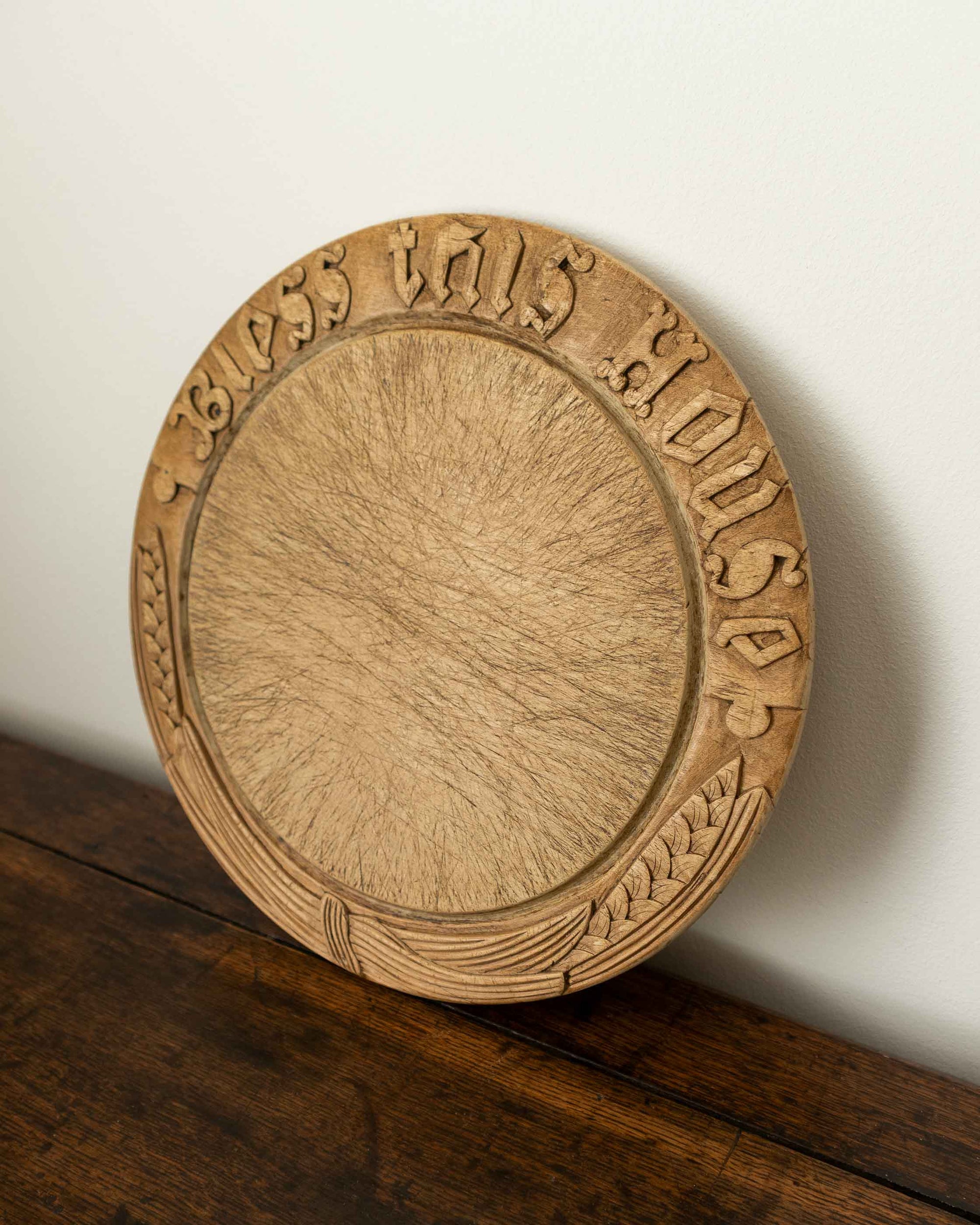 Wooden breadboard with carved text on a wooden surface