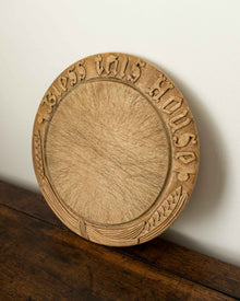 Wooden breadboard with carved text on a wooden surface