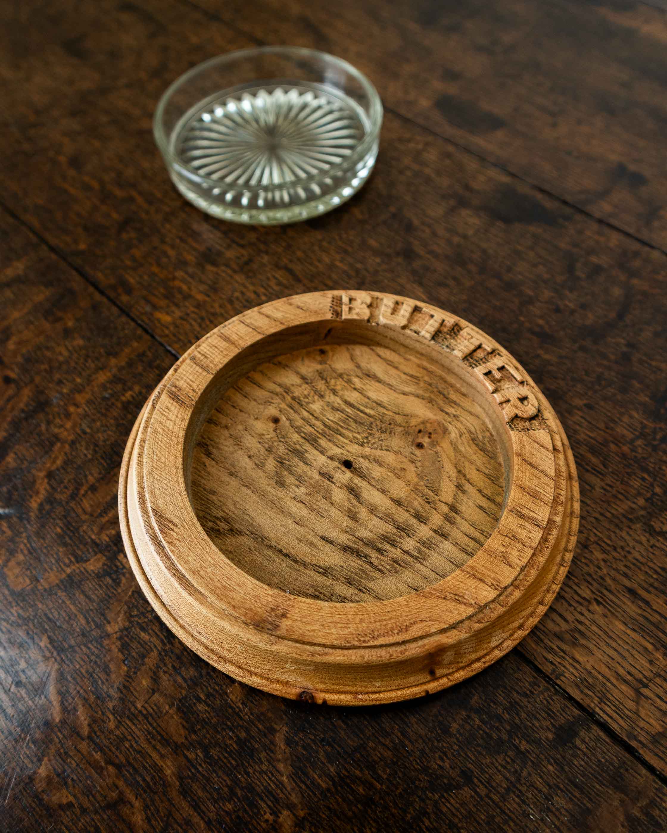 Wooden butter dish with a glass insert on a wooden surface
