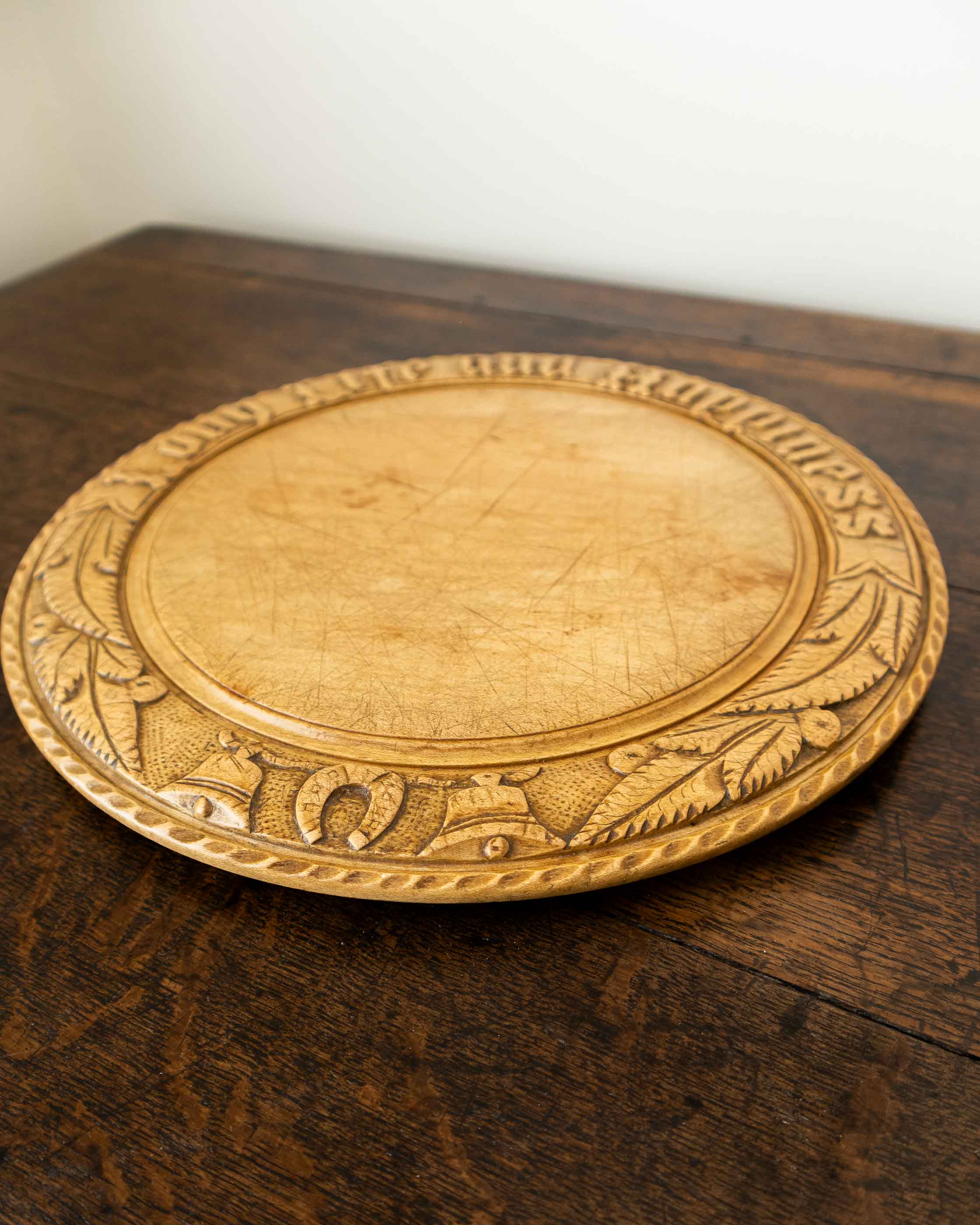 Wooden breadboard with carved text on a wooden surface