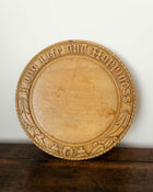 Wooden breadboard with carved text on a wooden surface