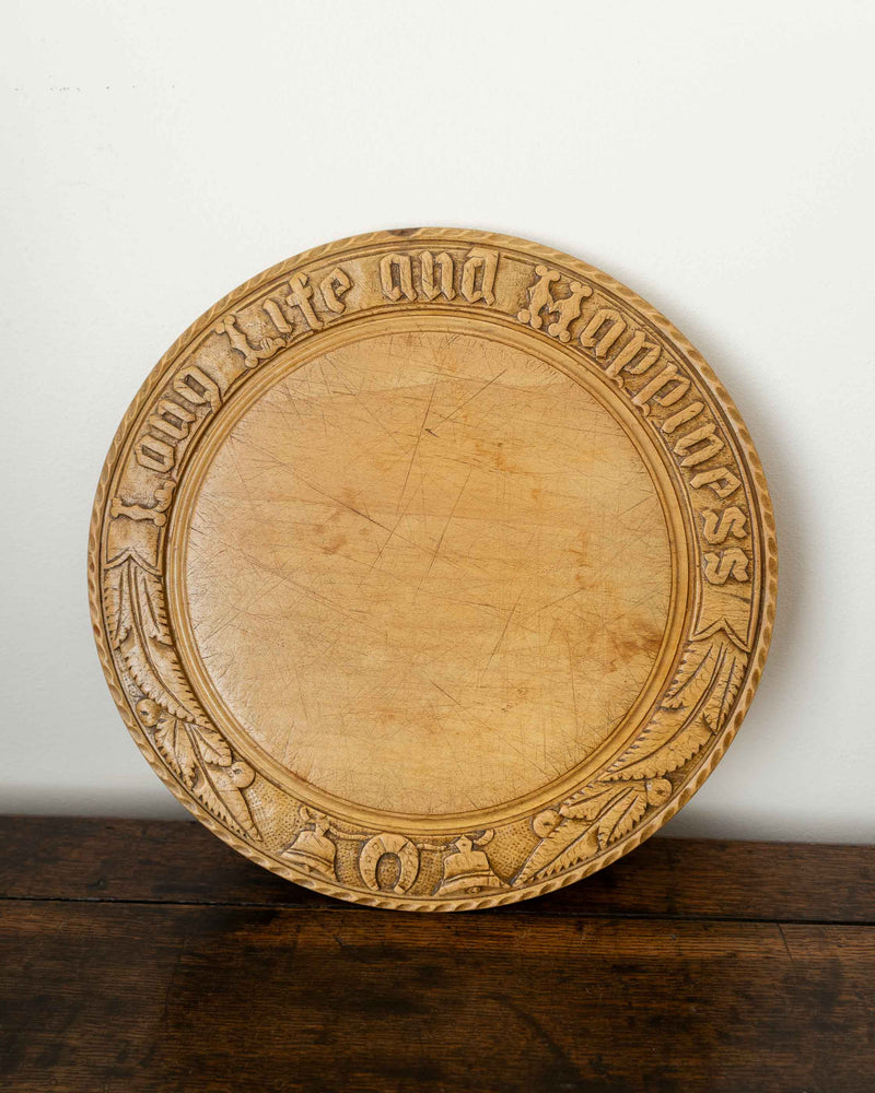Wooden breadboard with carved text on a wooden surface