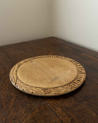 Wooden breadboard with carved text on a wooden surface