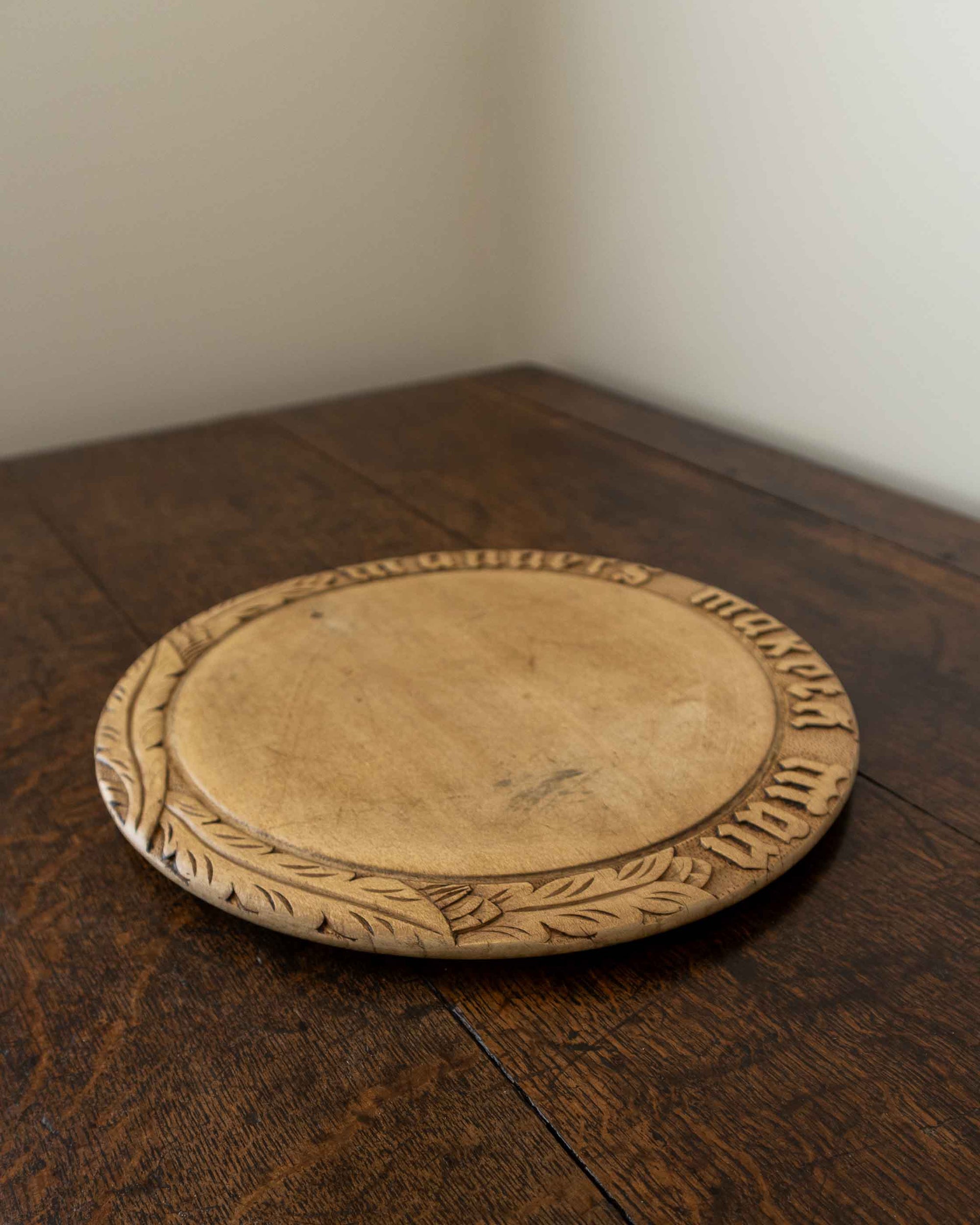 Wooden breadboard with carved text on a wooden surface
