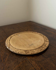 Wooden breadboard with carved text on a wooden surface