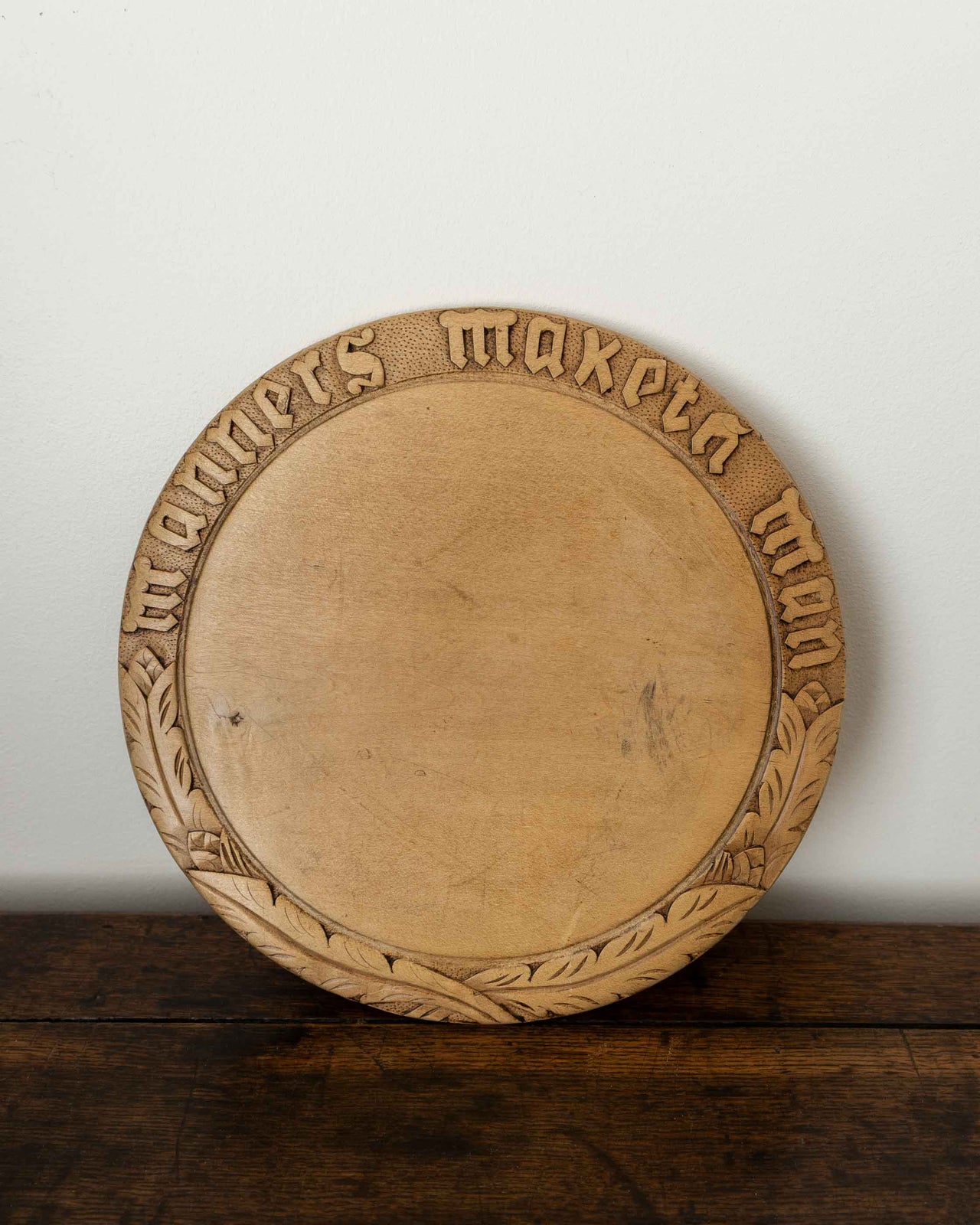 Wooden breadboard with carved text on a wooden surface