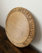 Wooden breadboard with carved text on a wooden surface