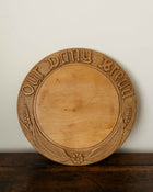 Wooden breadboard with carved text on a wooden surface