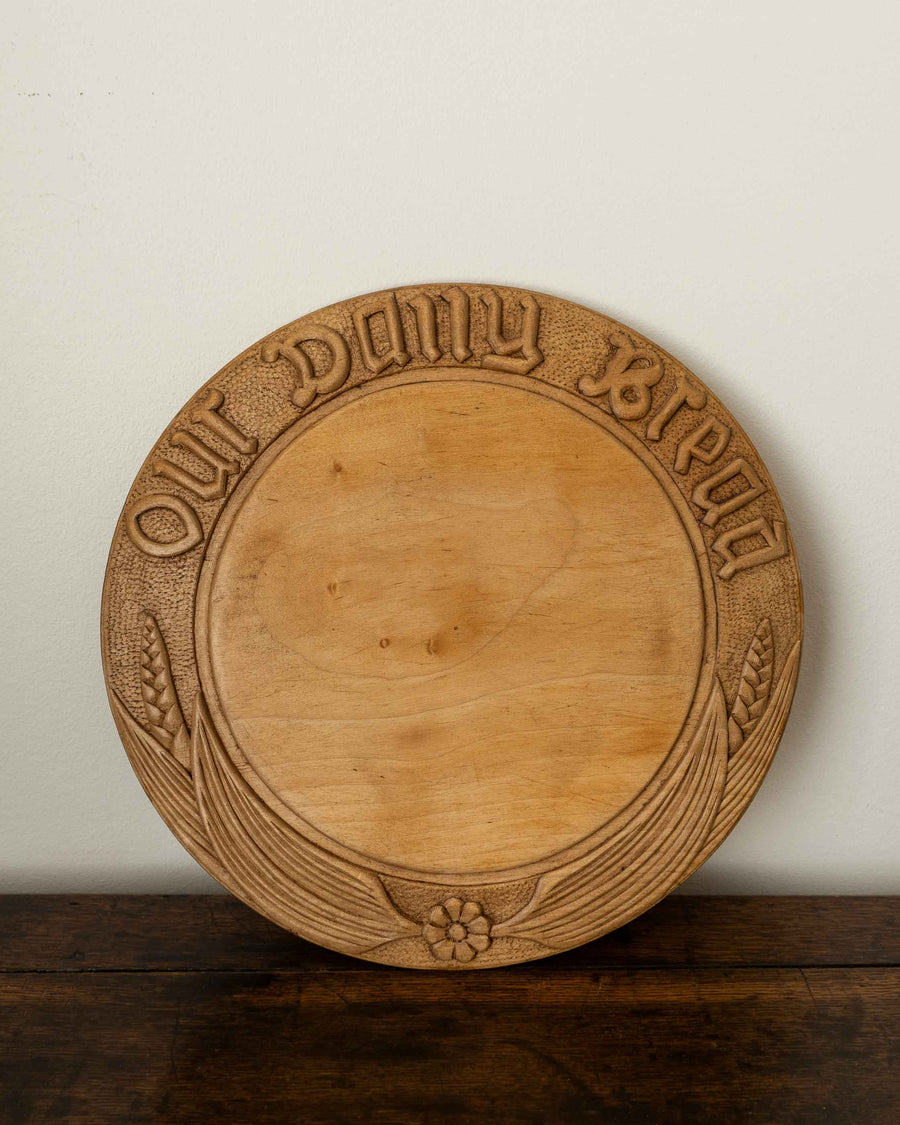 Wooden breadboard with carved text on a wooden surface
