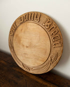 Wooden breadboard with carved text on a wooden surface