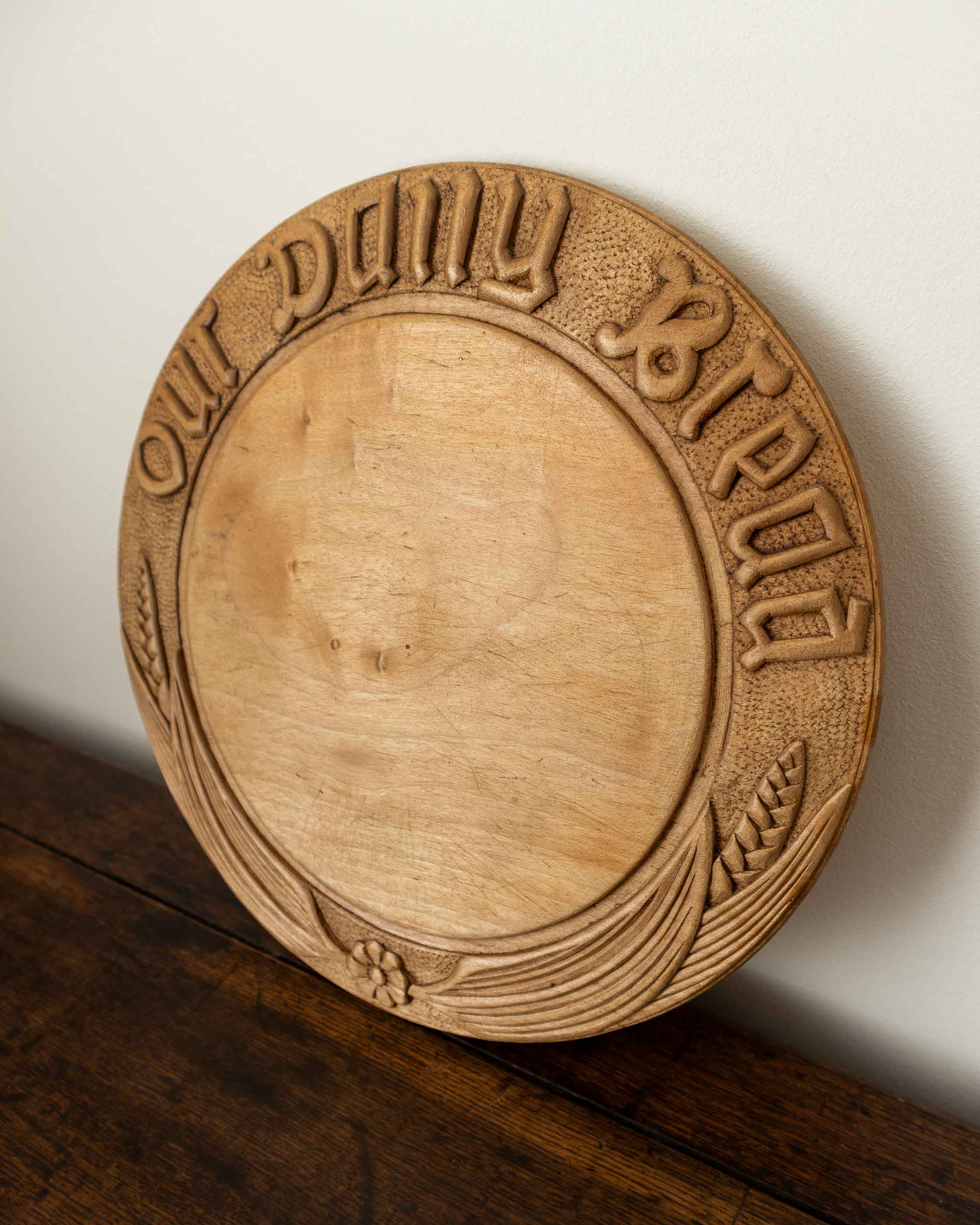 Wooden breadboard with carved text on a wooden surface