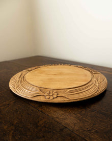 Wooden breadboard with carved text on a wooden surface