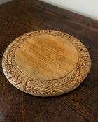 Wooden breadboard with carved text on a wooden surface