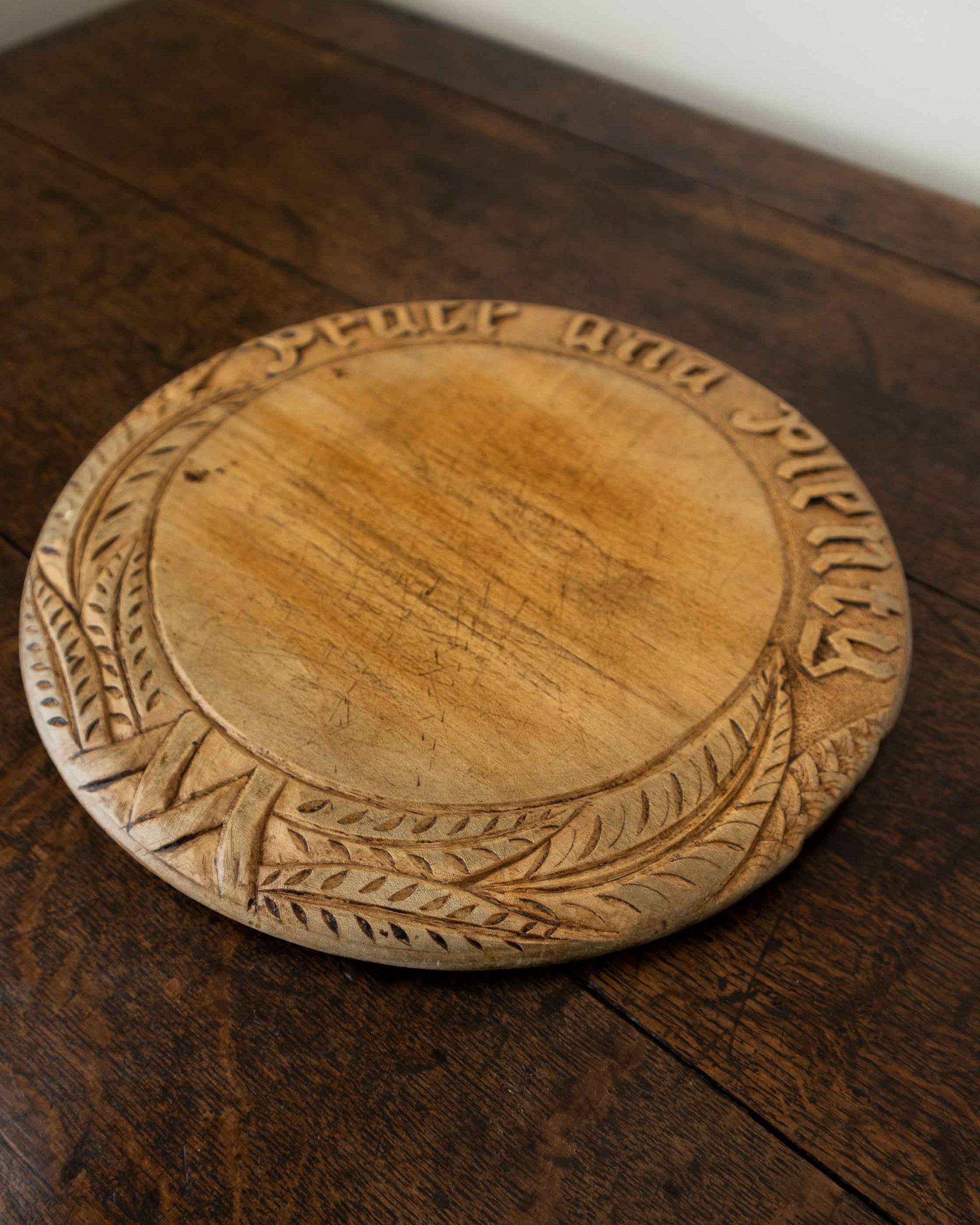Wooden breadboard with carved text on a wooden surface