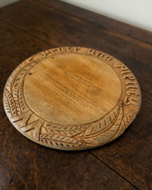 Wooden breadboard with carved text on a wooden surface