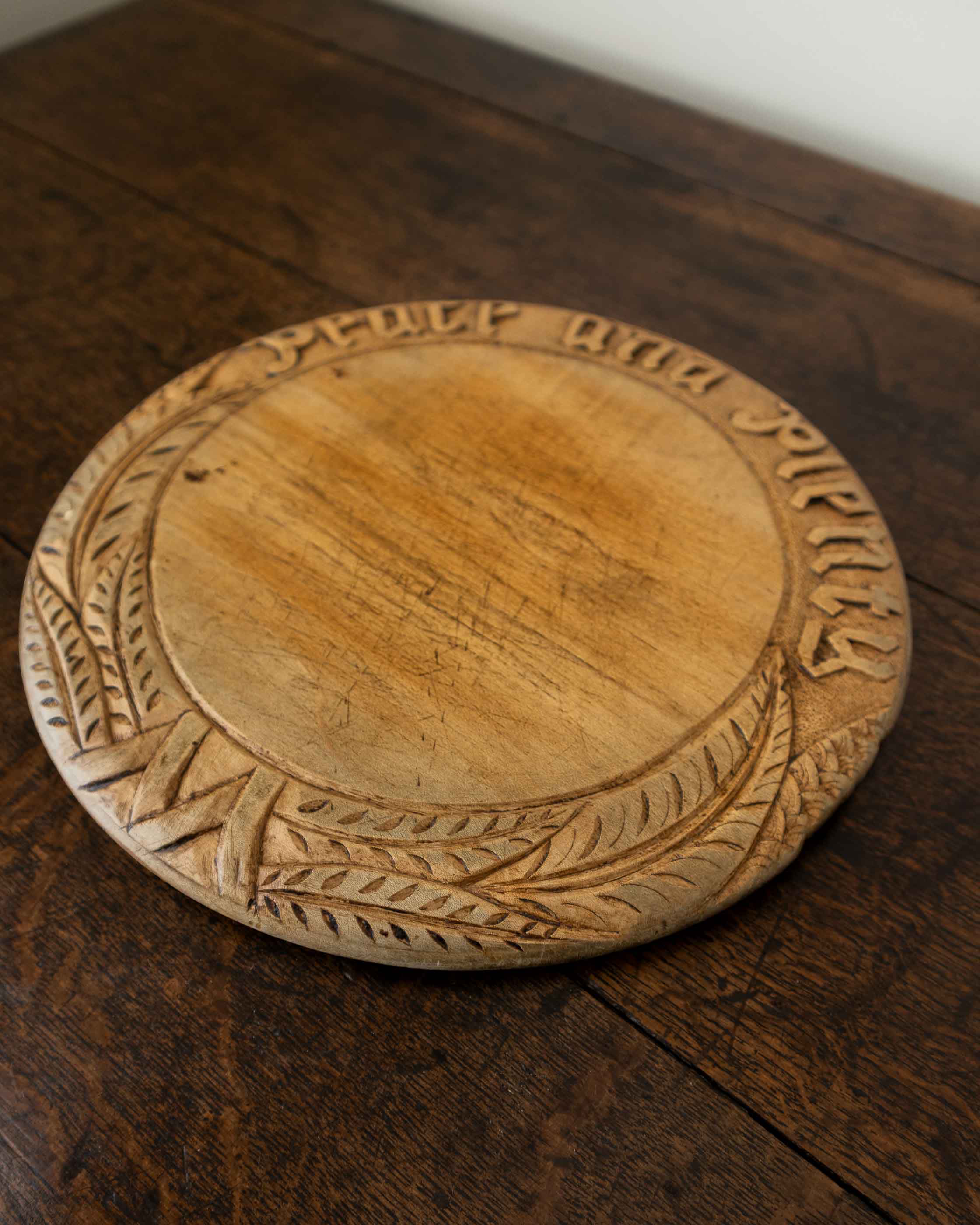 Wooden breadboard with carved text on a wooden surface