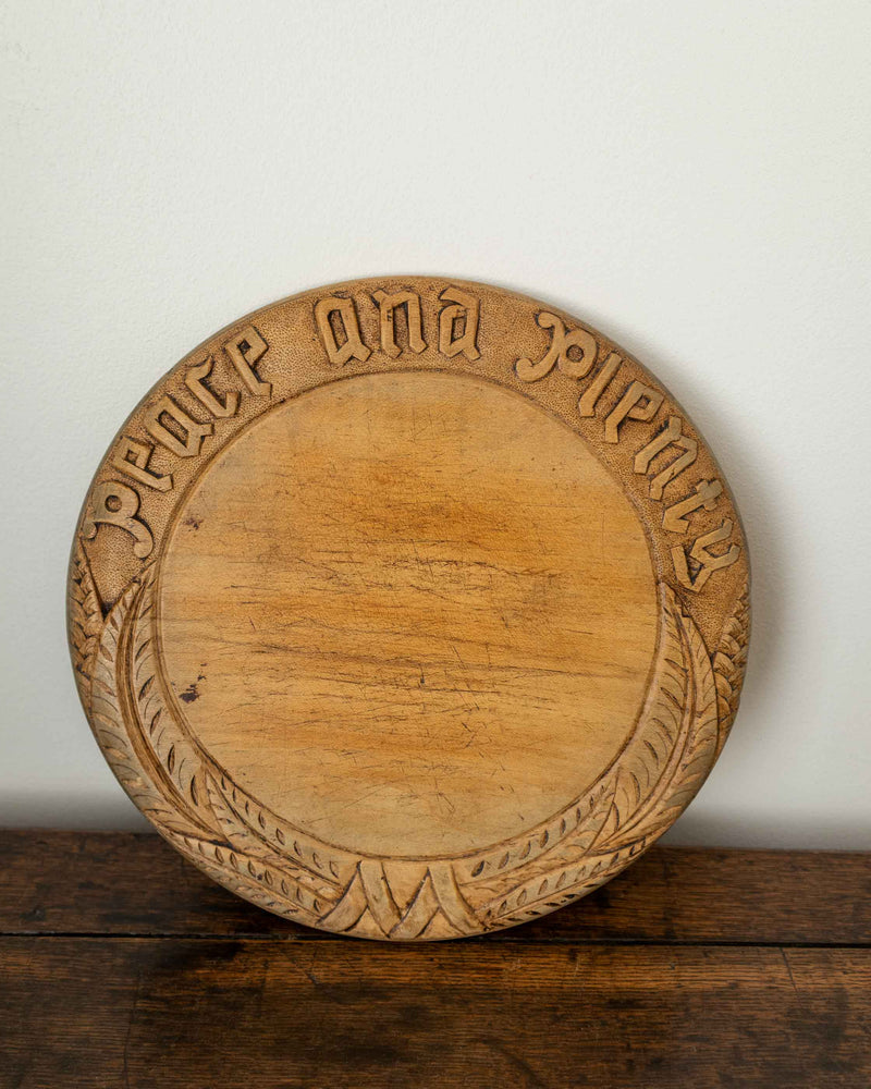Wooden breadboard with carved text on a wooden surface