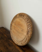 Wooden breadboard with carved text on a wooden surface
