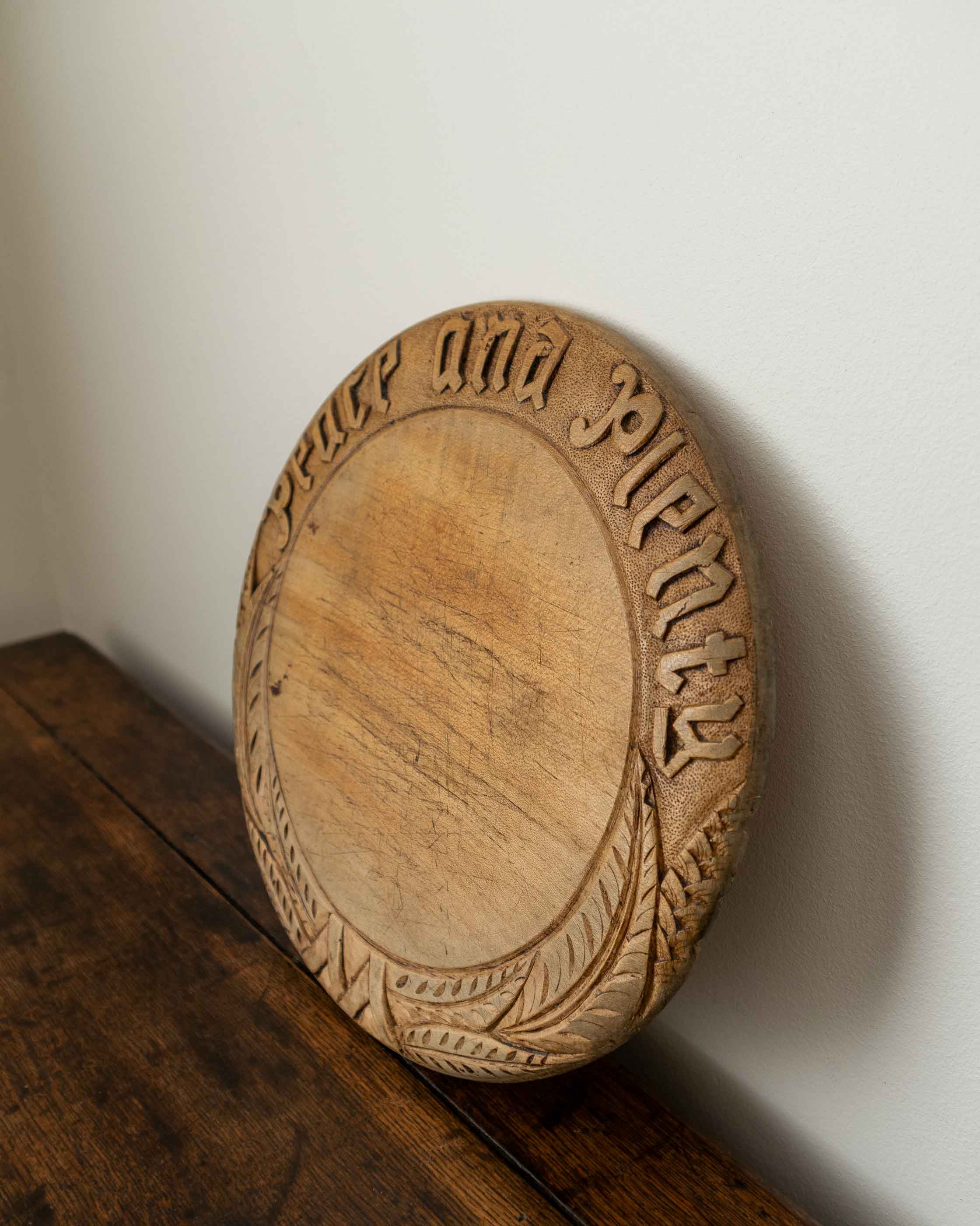 Wooden breadboard with carved text on a wooden surface