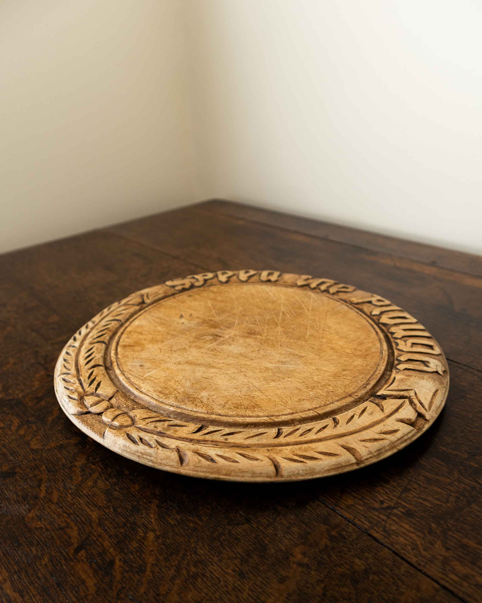 Wooden breadboard with carved text on a wooden surface