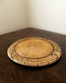 Wooden breadboard with carved text on a wooden surface