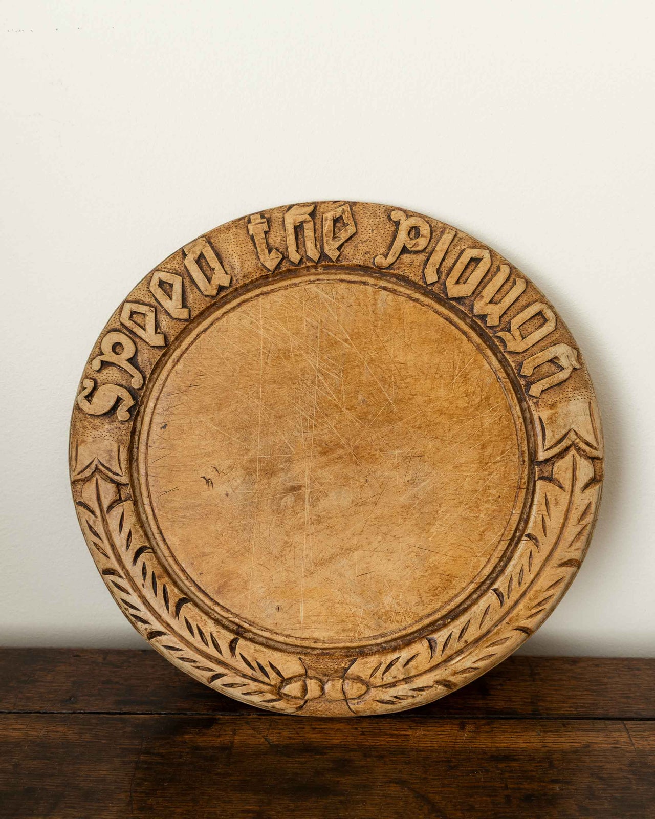 Wooden breadboard with carved text on a wooden surface