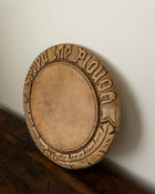 Wooden breadboard with carved text on a wooden surface