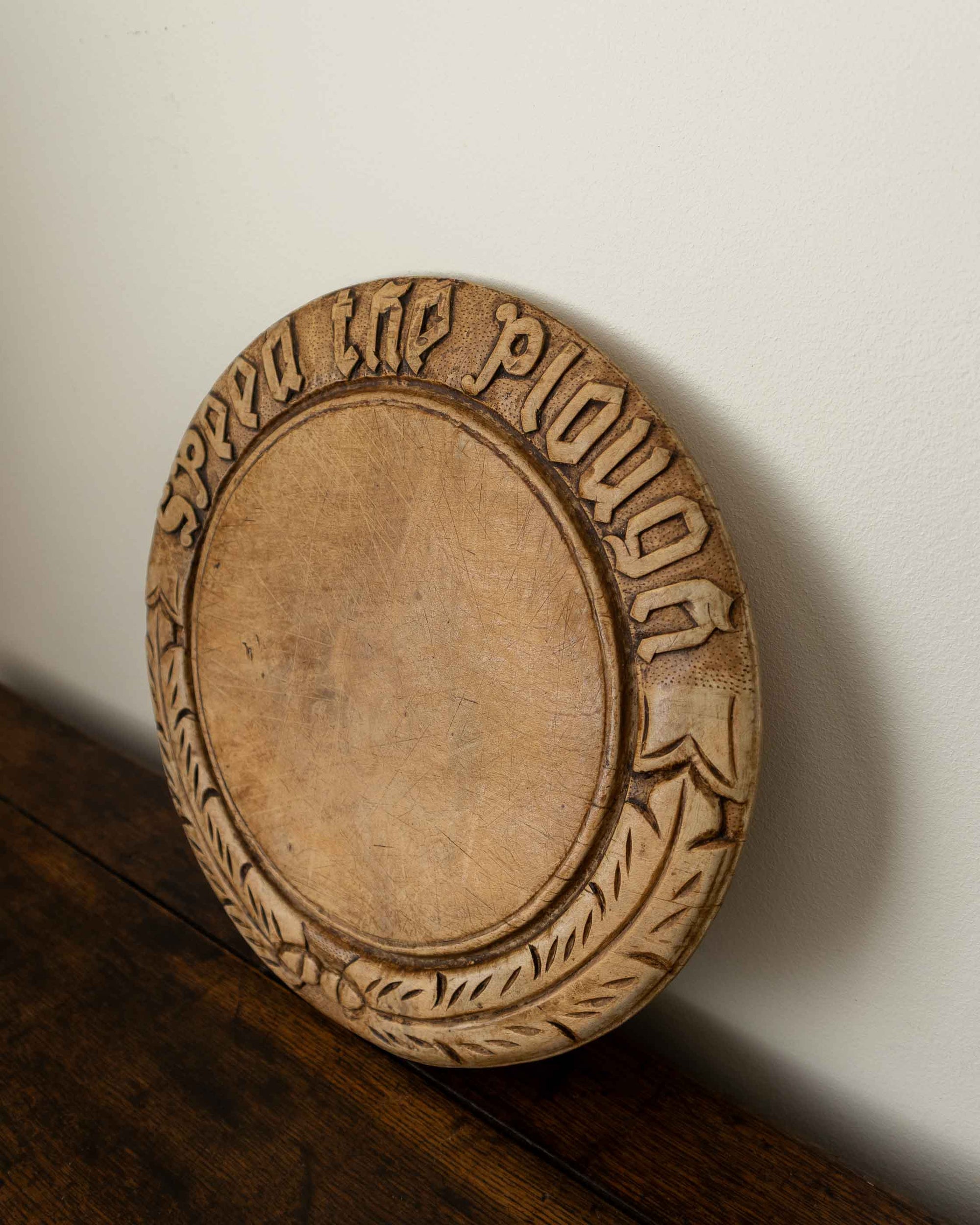 Wooden breadboard with carved text on a wooden surface
