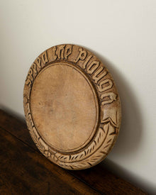 Wooden breadboard with carved text on a wooden surface