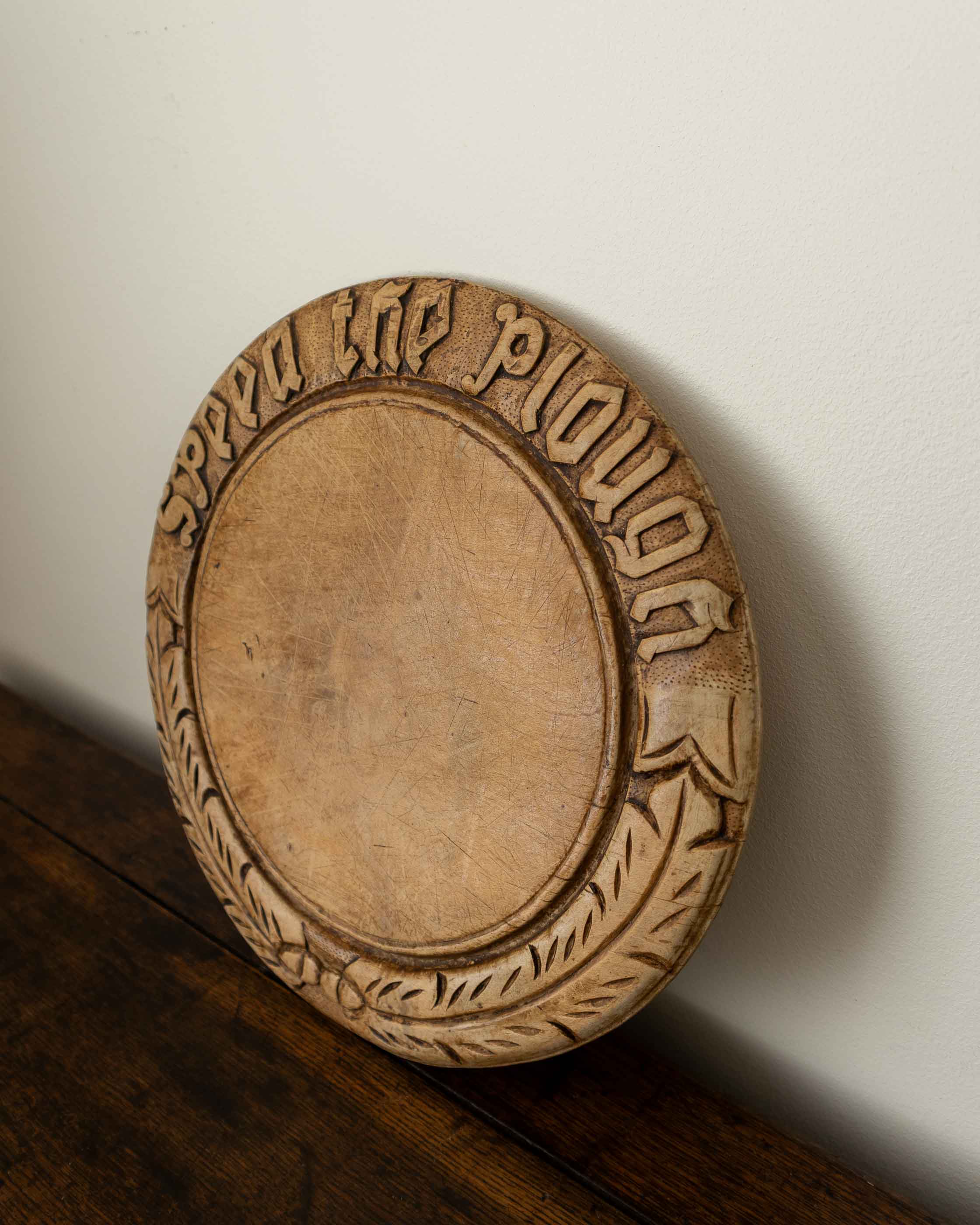 Wooden breadboard with carved text on a wooden surface