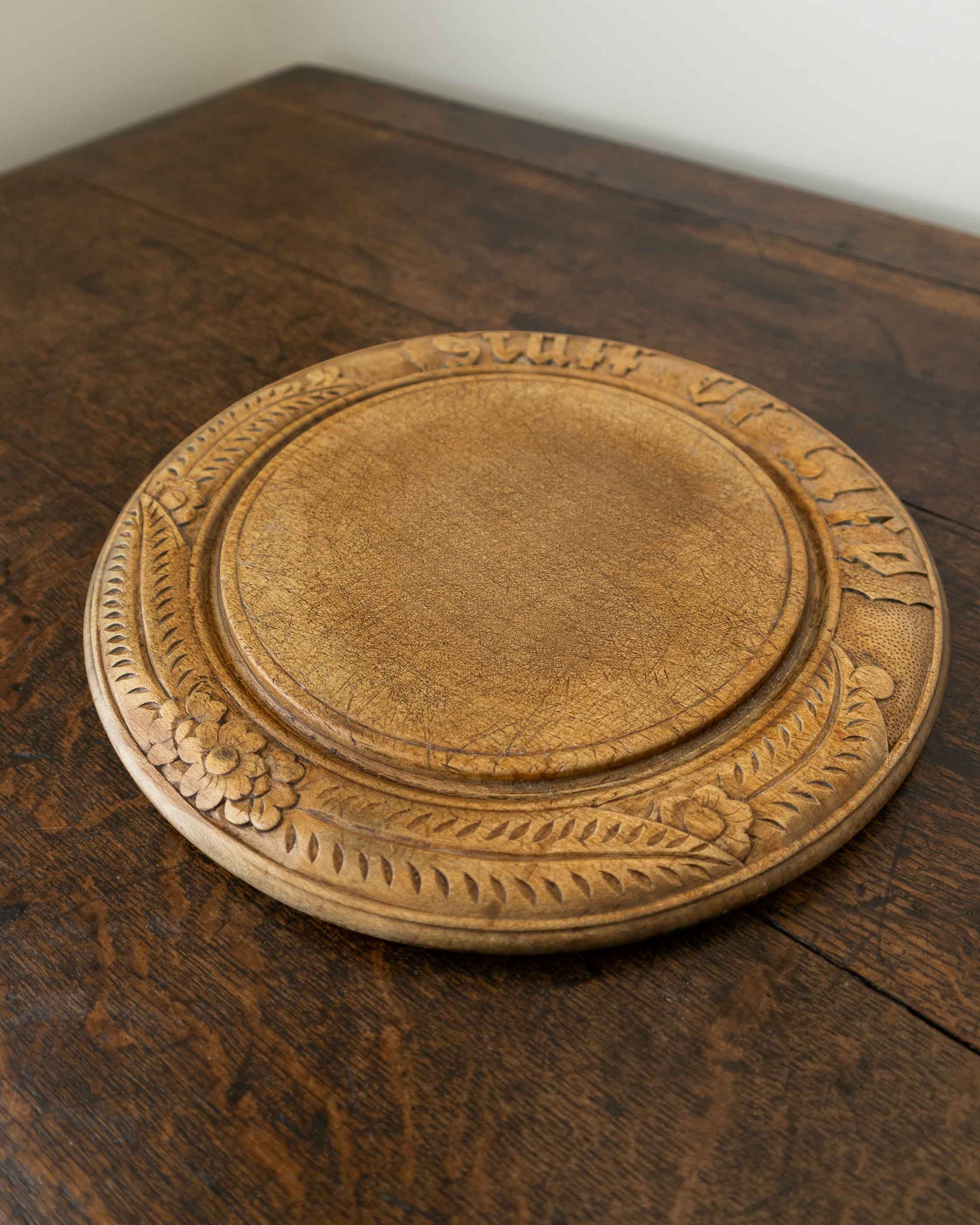Wooden breadboard with carved text on a wooden surface