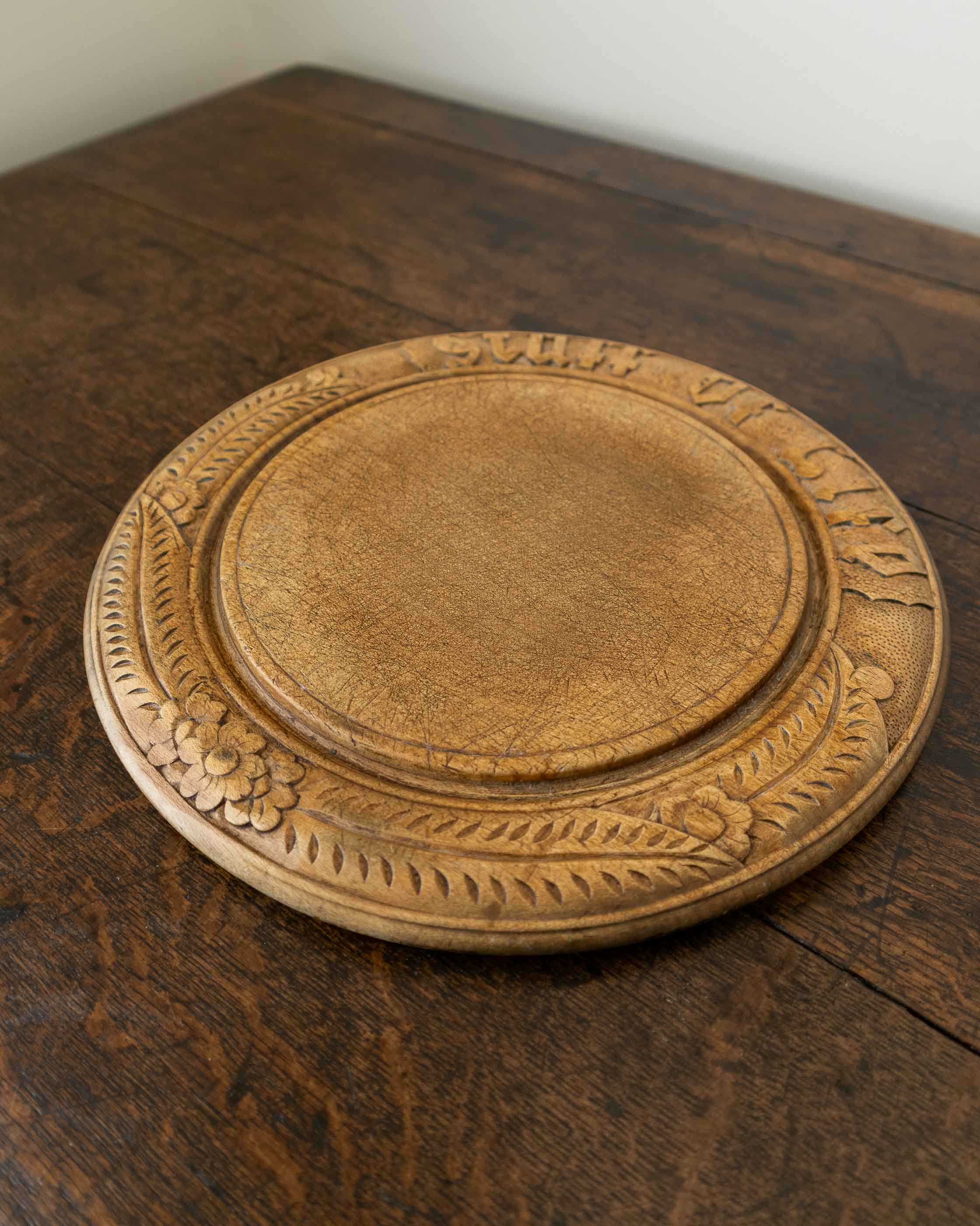Wooden breadboard with carved text on a wooden surface