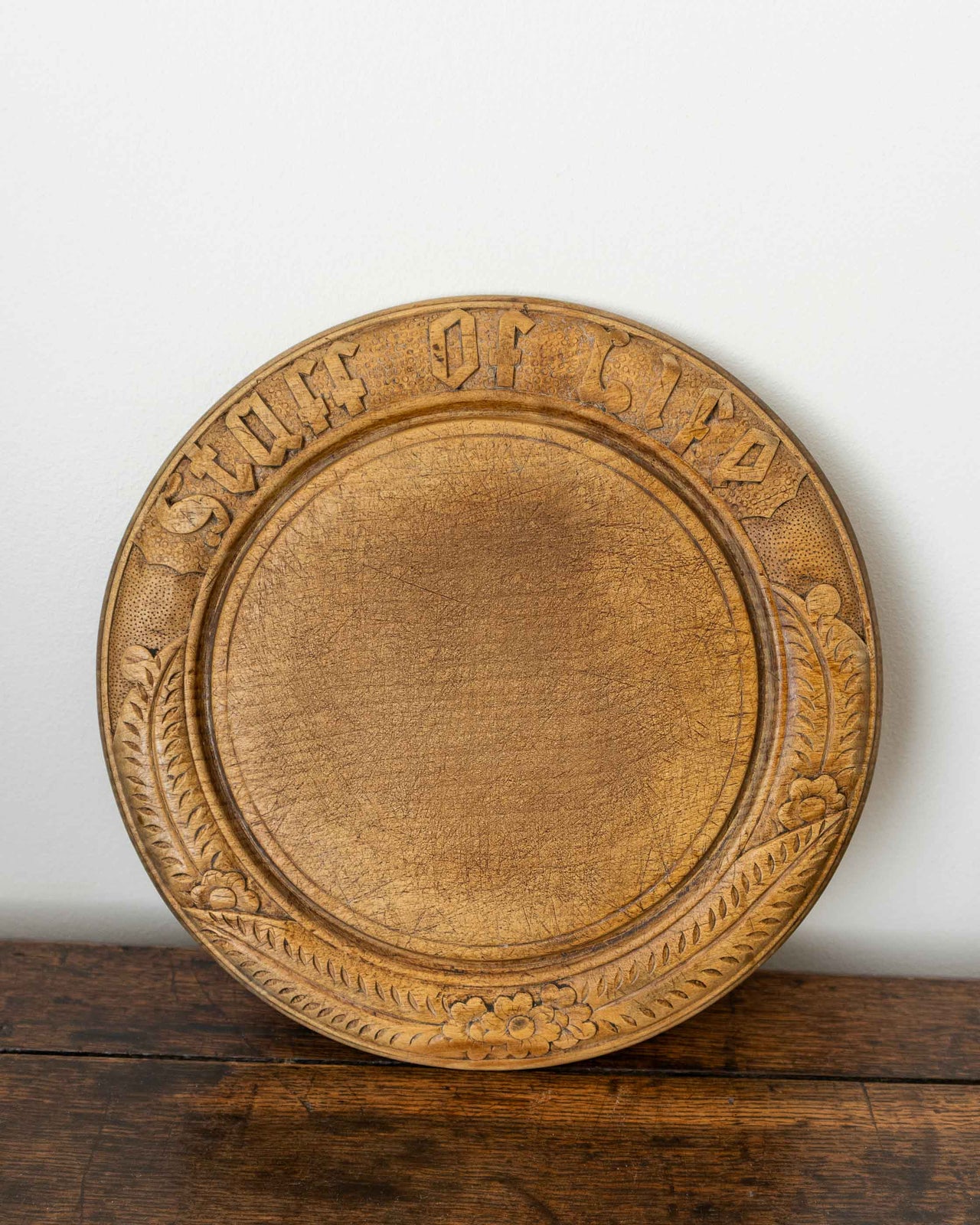 Wooden breadboard with carved text on a wooden surface