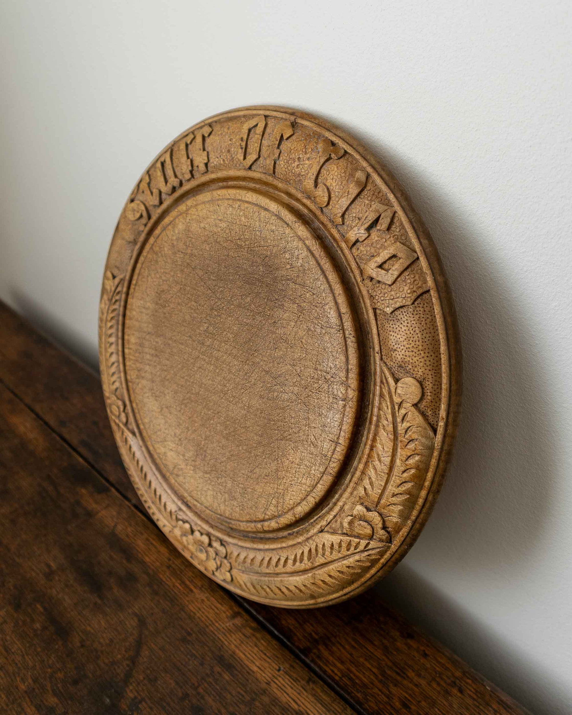 Wooden breadboard with carved text on a wooden surface