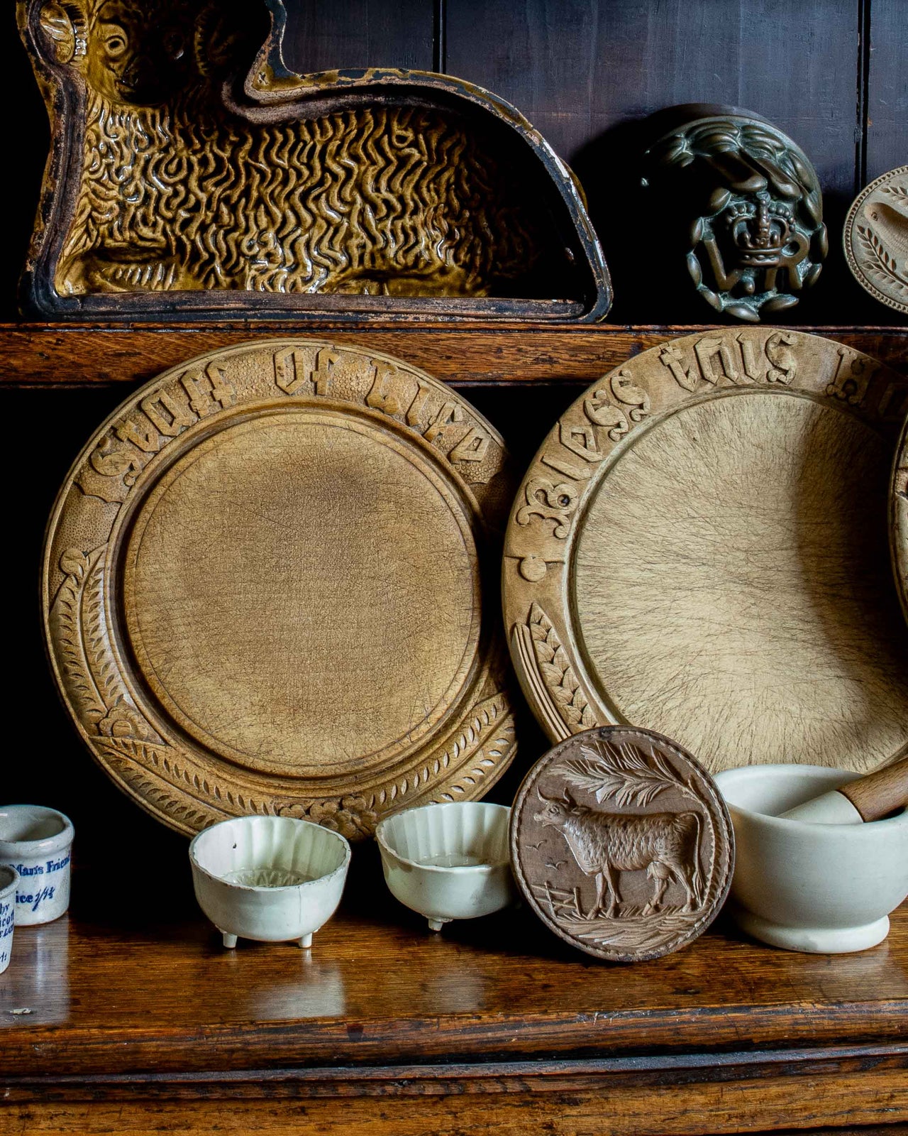 Collection of wooden breadboards and moulds with embossed designs on a wooden shelf.