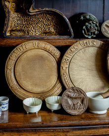 Collection of wooden breadboards and moulds with embossed designs on a wooden shelf.