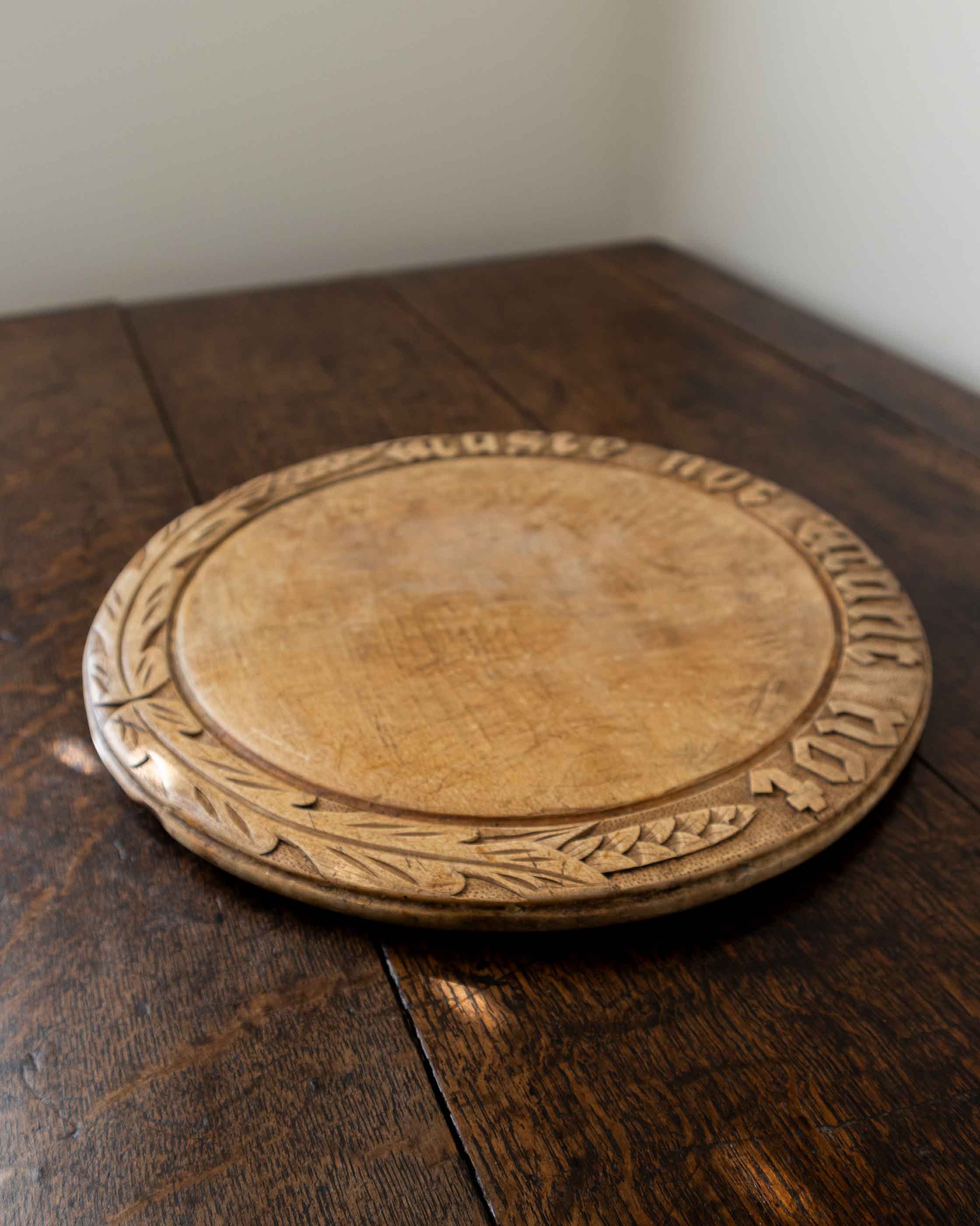 Wooden breadboard with carved text on a wooden surface