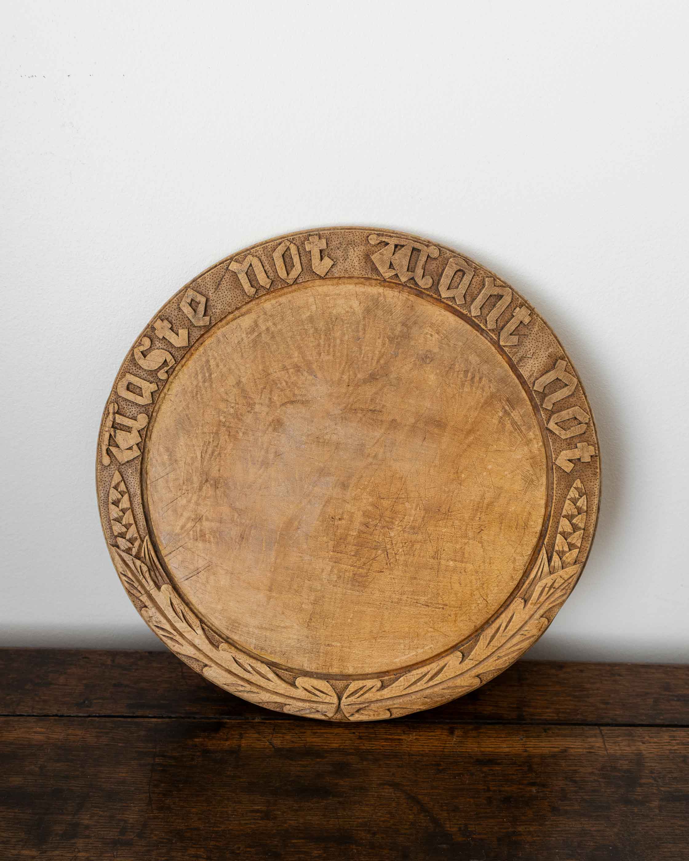 Wooden breadboard with carved text on a wooden surface