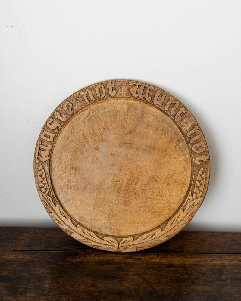 Wooden breadboard with carved text on a wooden surface