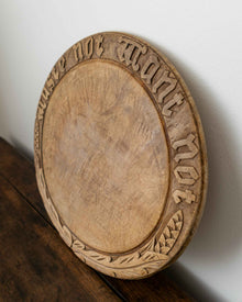 Wooden breadboard with carved text on a wooden surface