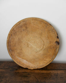 Round wooden breadboard on a wooden surface with a white background