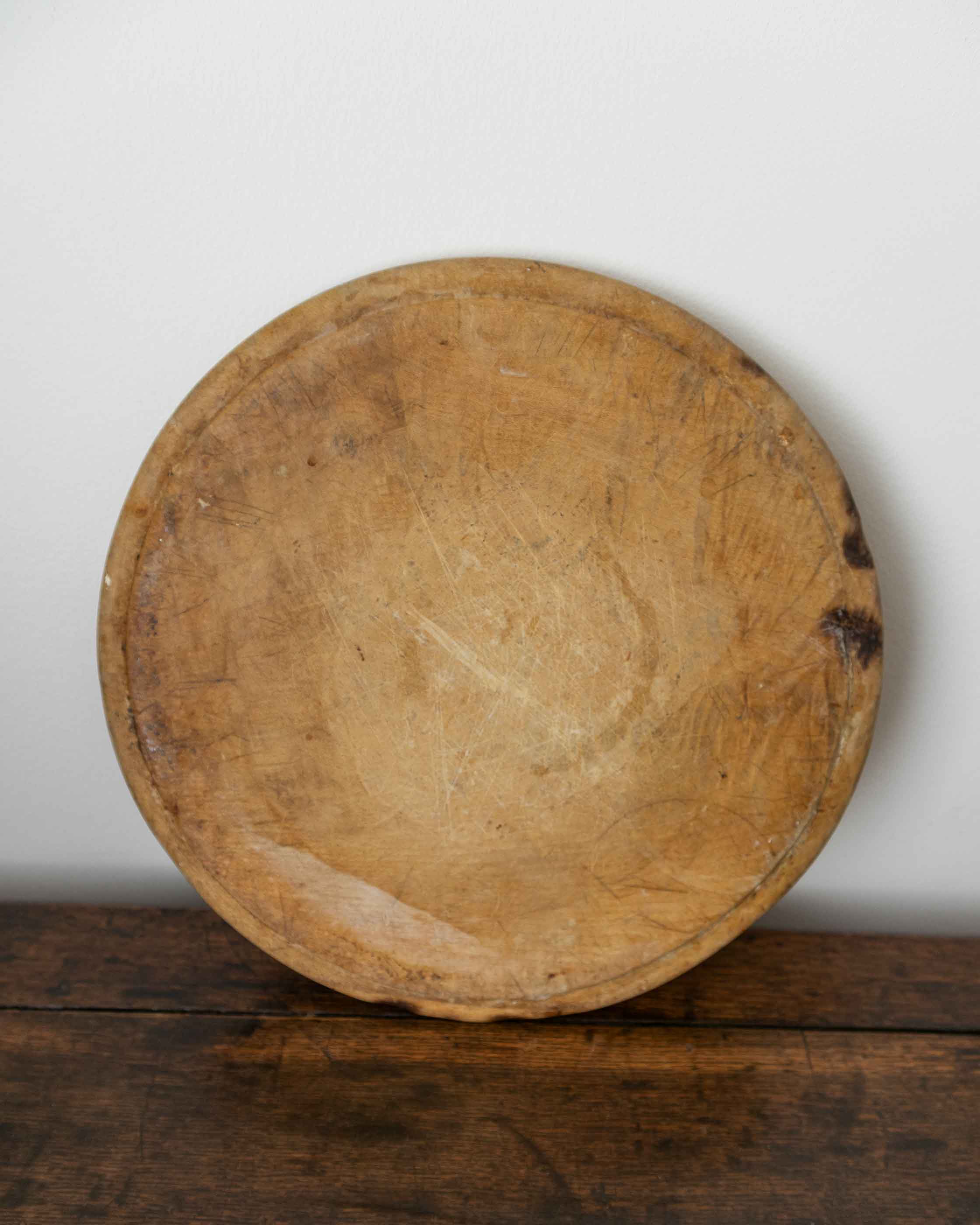 Round wooden breadboard on a wooden surface with a white background