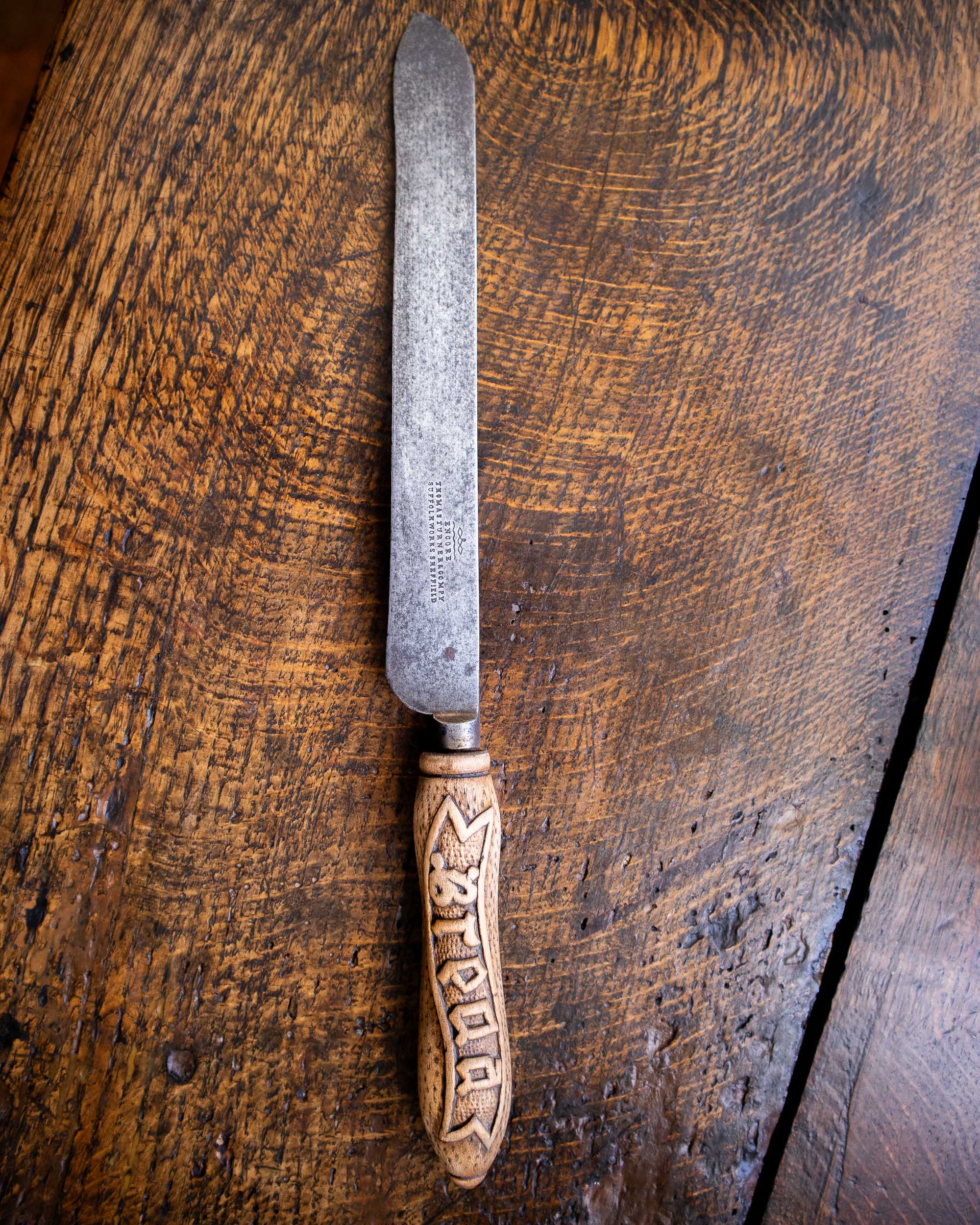 Bread knife with a decorative handle on a wooden surface