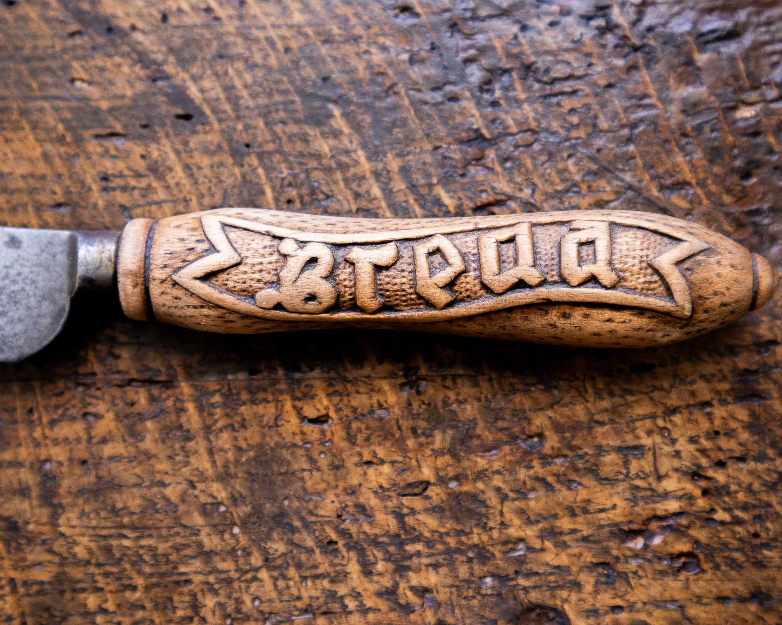 Knife with a wooden handle engraved with 'Bread' on a wooden surface