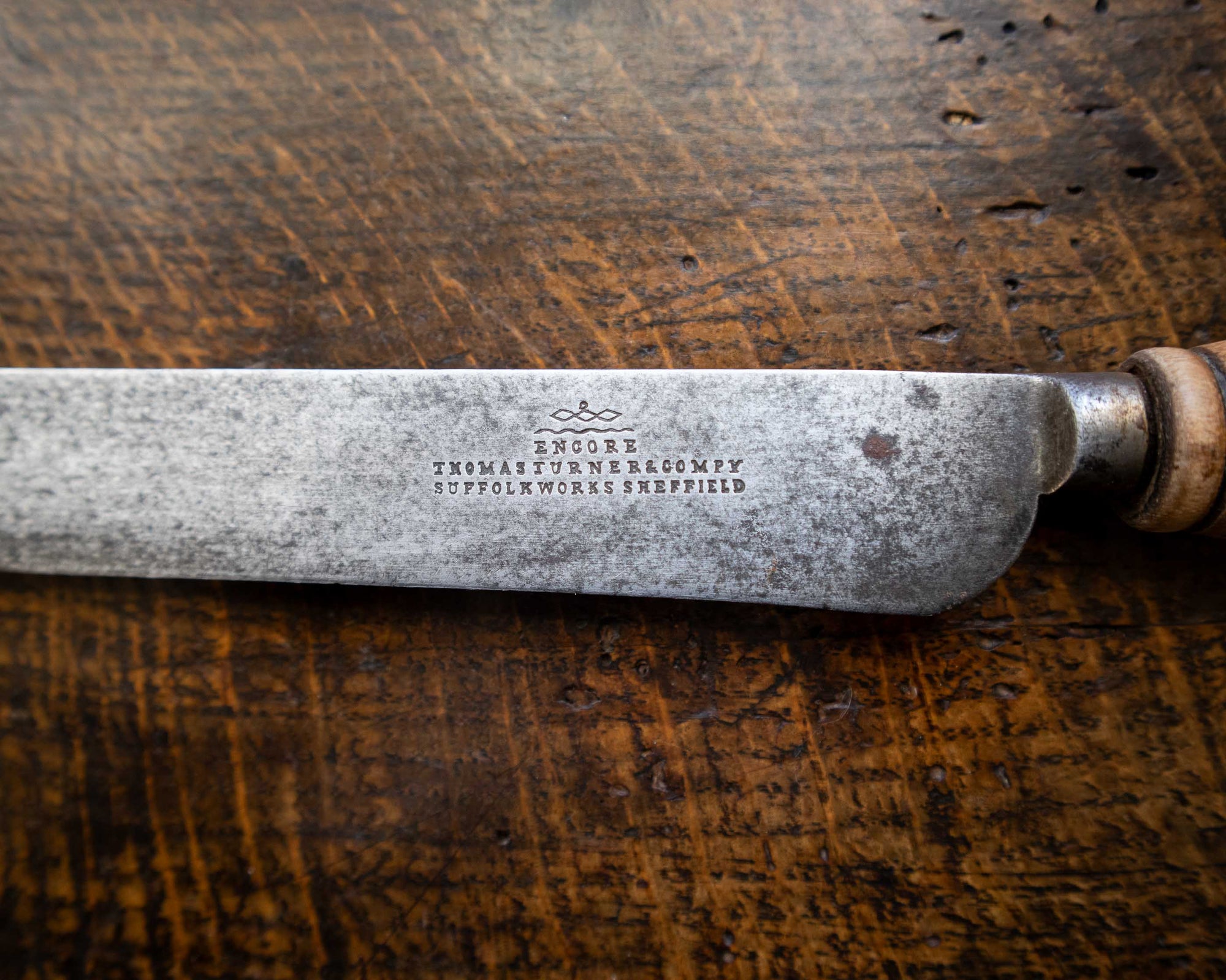 Vintage knife with engraved text on a wooden surface