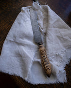 Bread knife with wooden handle on a white cloth on a wooden surface