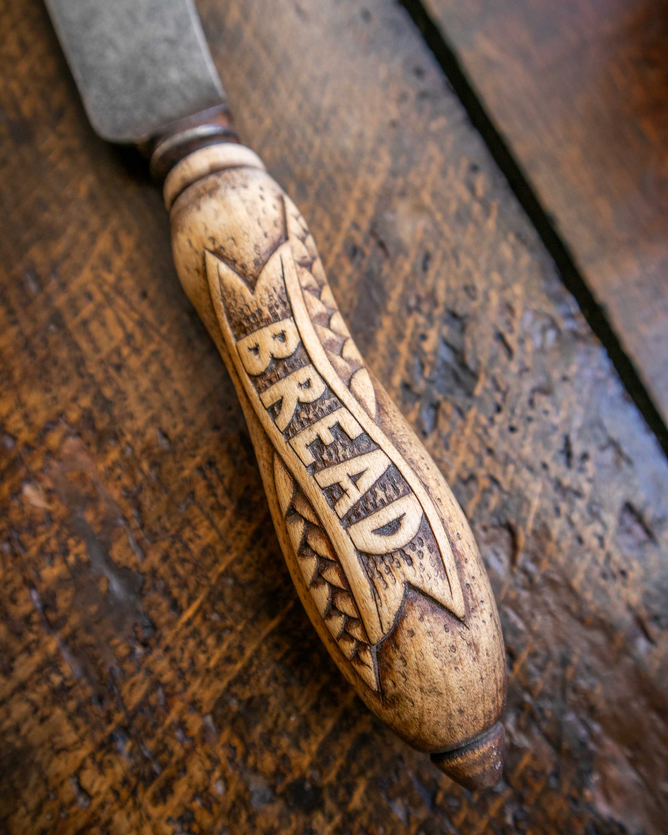 Wooden bread knife with engraved text on a wooden surface