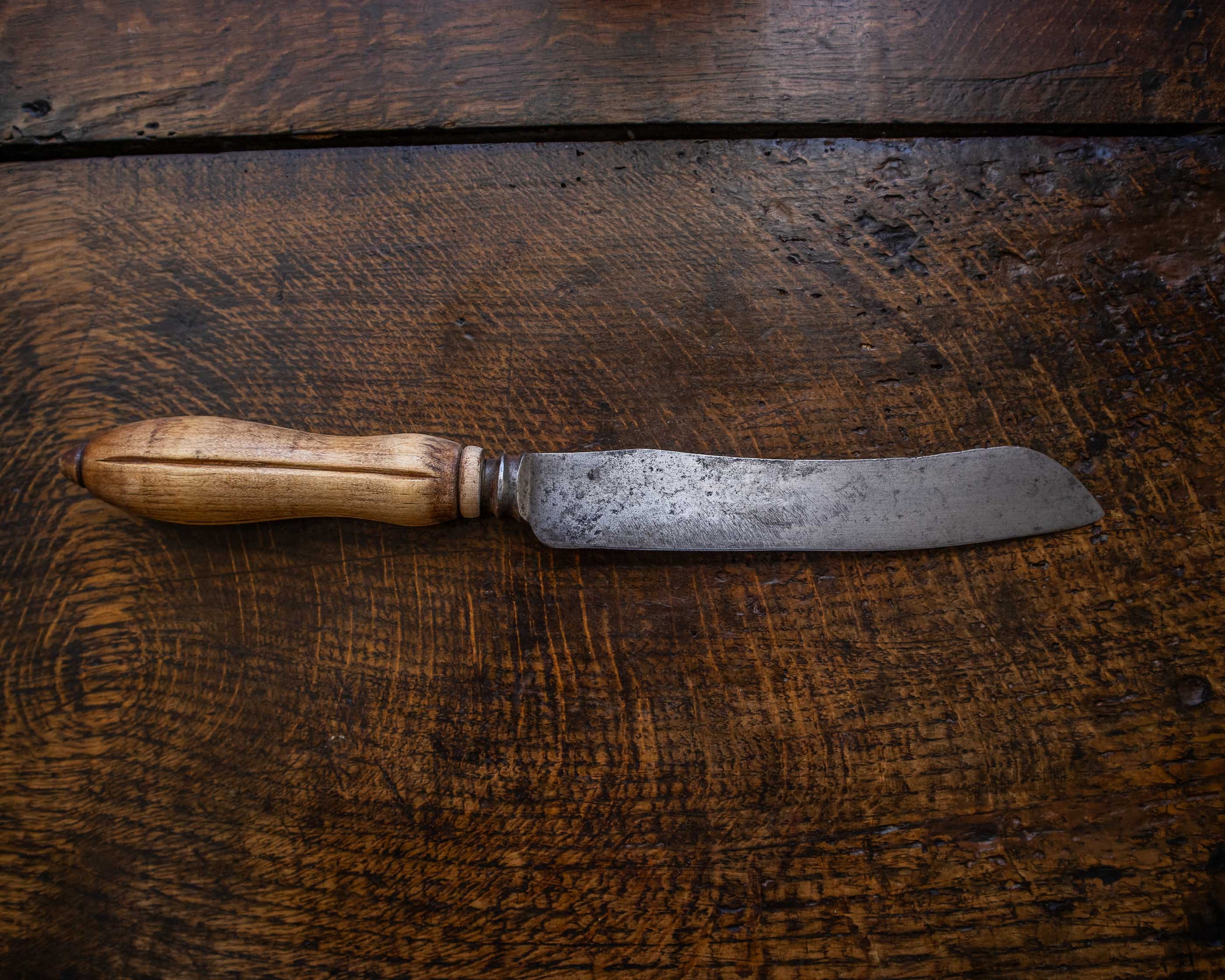 Bread knife with a wooden handle on a wooden surface
