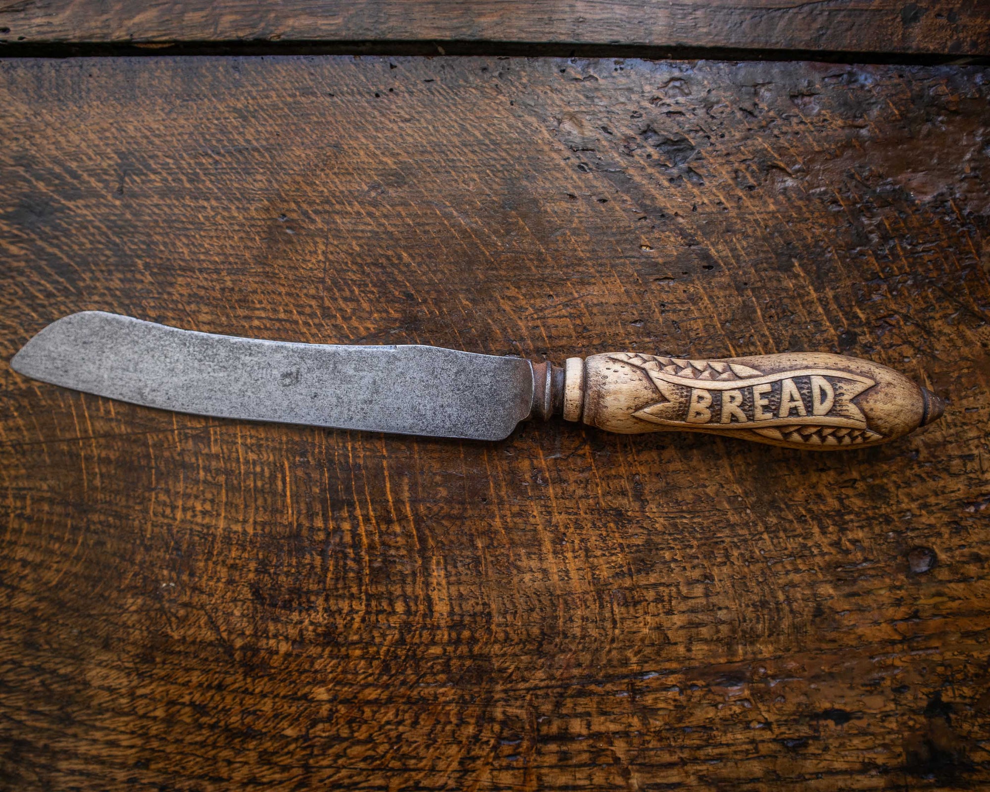 Bread knife with wooden handle on a wooden surface