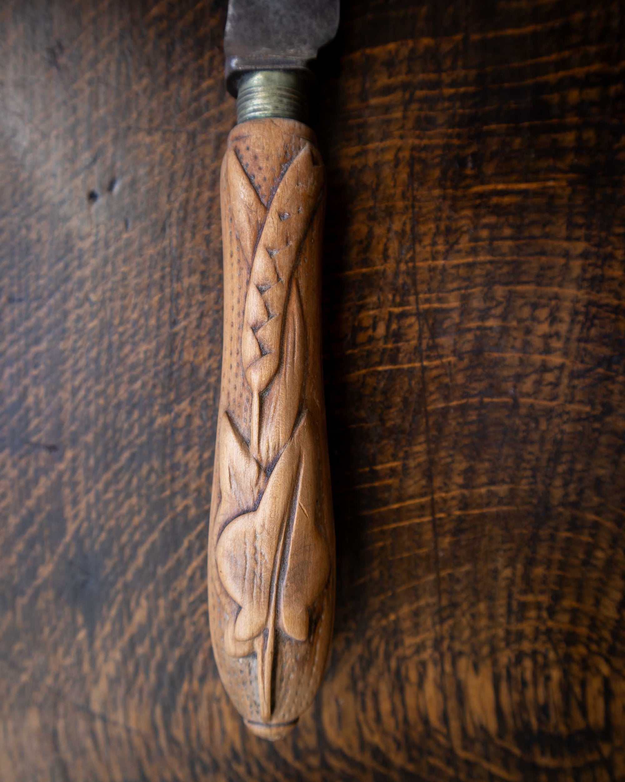 Wooden handle with carvings on a wooden background